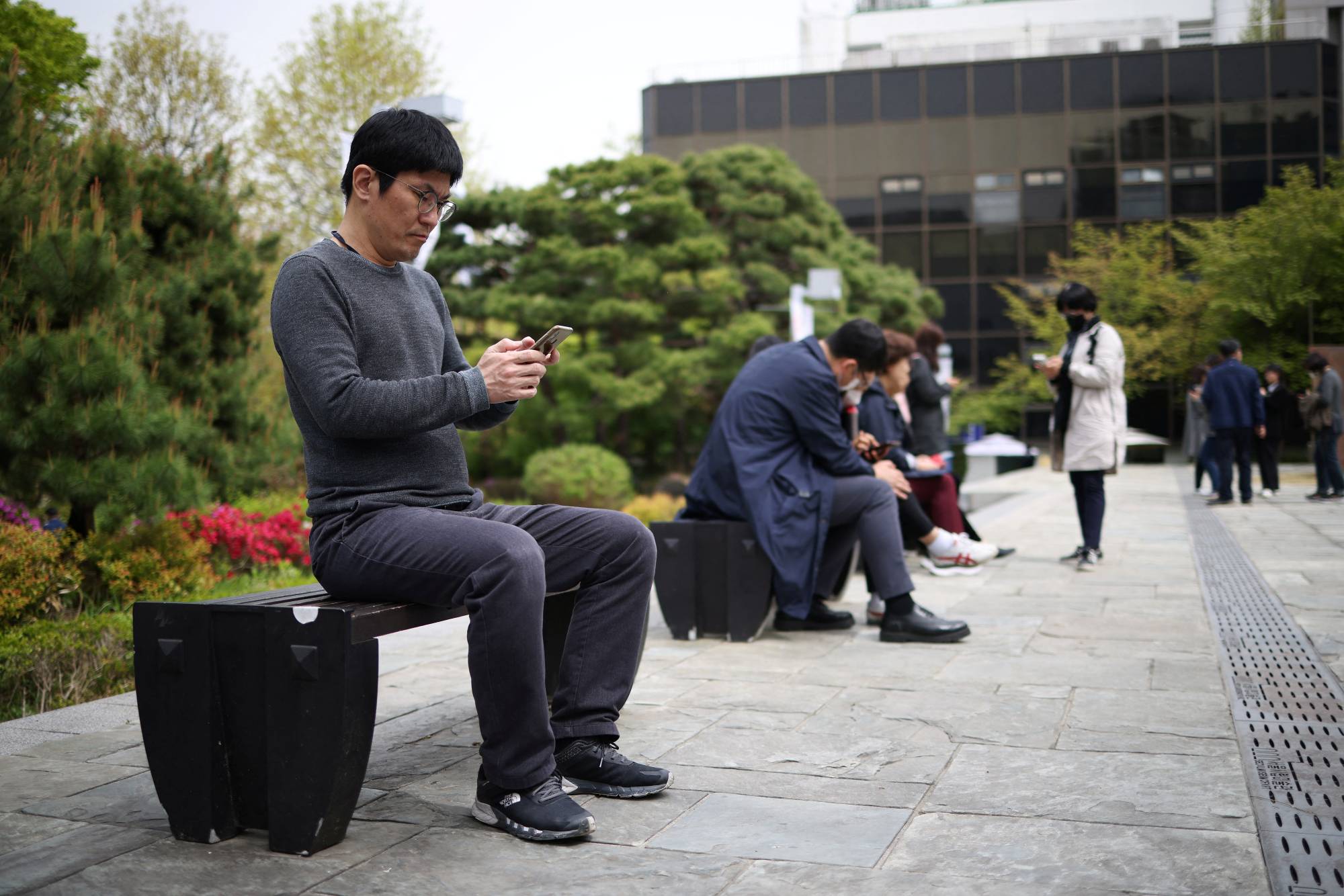 Kim Youngsuck, an office worker, looks at his mobile phone to check the local online banking app Toss at the Seoul Museum of Art during his lunch break in Seoul on April 13. | REUTERS