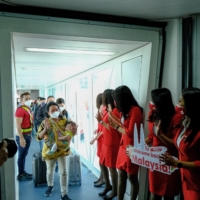 AirAsia staff welcome passengers after Malaysia allowed quarantine-free entry for fully vaccinated travelers on April 1, 2022. | BLOOMBERG