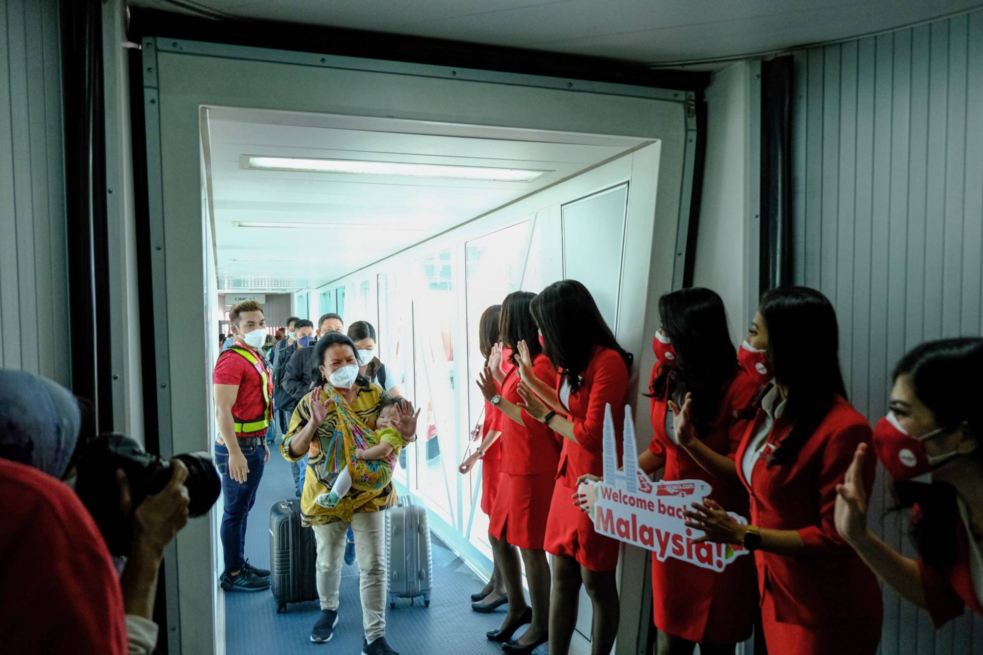 AirAsia staff welcome passengers after Malaysia allowed quarantine-free entry for fully vaccinated travelers on April 1, 2022. | Bloomberg