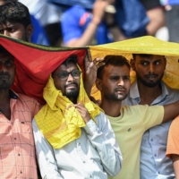 Spectators use scarves to shelter from the heat during a cricket match in Lucknow, India, on Saturday.  | AFP-JIJI