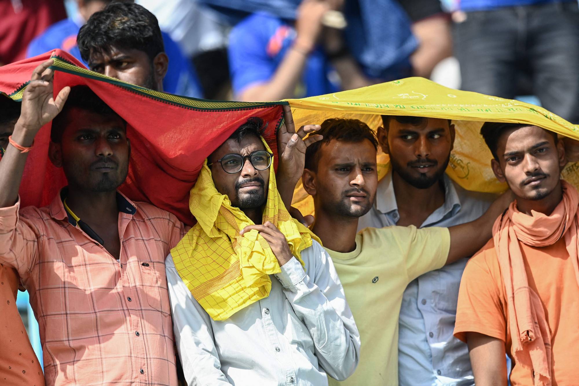 Spectators use scarves to shelter from the heat during a cricket match in Lucknow, India, on Saturday.  | AFP-JIJI