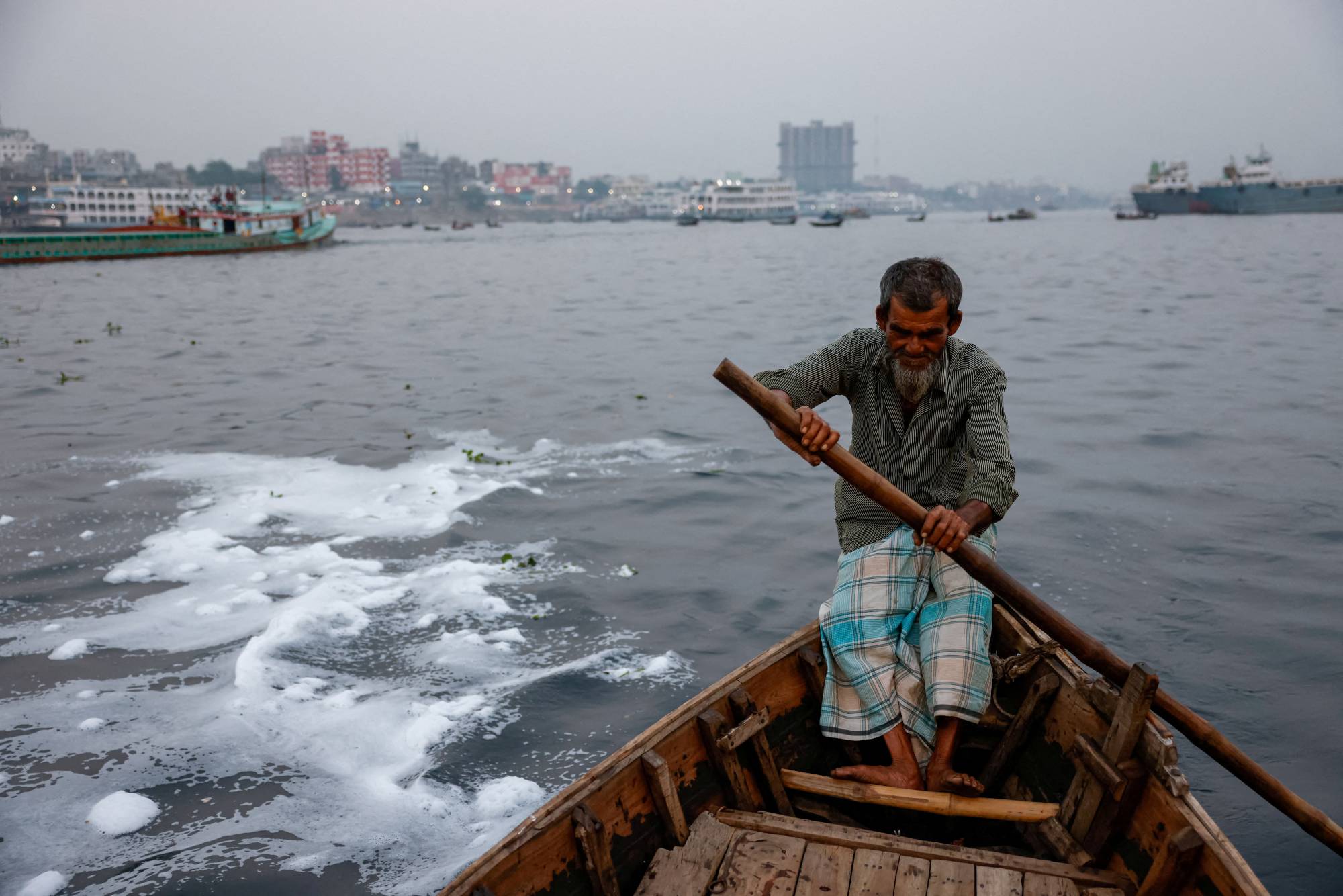 Ferryman Abdul Karim, 72, rides his boat in the Buriganga River near the Sadarghat area in Dhaka. The Buriganga, or the 'Old Ganges,' is so polluted that its water appears pitch black, except during the monsoon months, and it emits a foul stench through the year. | REUTERS