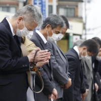People offer prayers for the victims of a 2005 train derailment in Amagasaki, Hyogo Prefecture, on its 18th anniversary on Tuesday. | KYODO