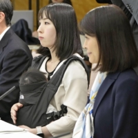 Shoko Takahashi (center), founder of personal genome company Genequest, attends a government meeting with her baby at the Prime Minister\'s Office in Tokyo on Thursday. | KYODO