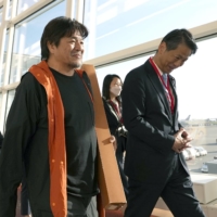 Naoyuki Kawahara (center), head of that nonprofit organization Rocinantes that has been involved in providing medical support in Sudan, arrives at Tokyo\'s Haneda Airport with other evacuees from the war-torn country on Saturday morning. | KYODO