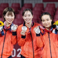 Kasumi Ishikawa (center) poses with teammates Miu Hirano (left) and Mima Ito after earning the silver medal in the women\'s team table tennis competition during the Tokyo Olympics in August 2021. | KYODO
