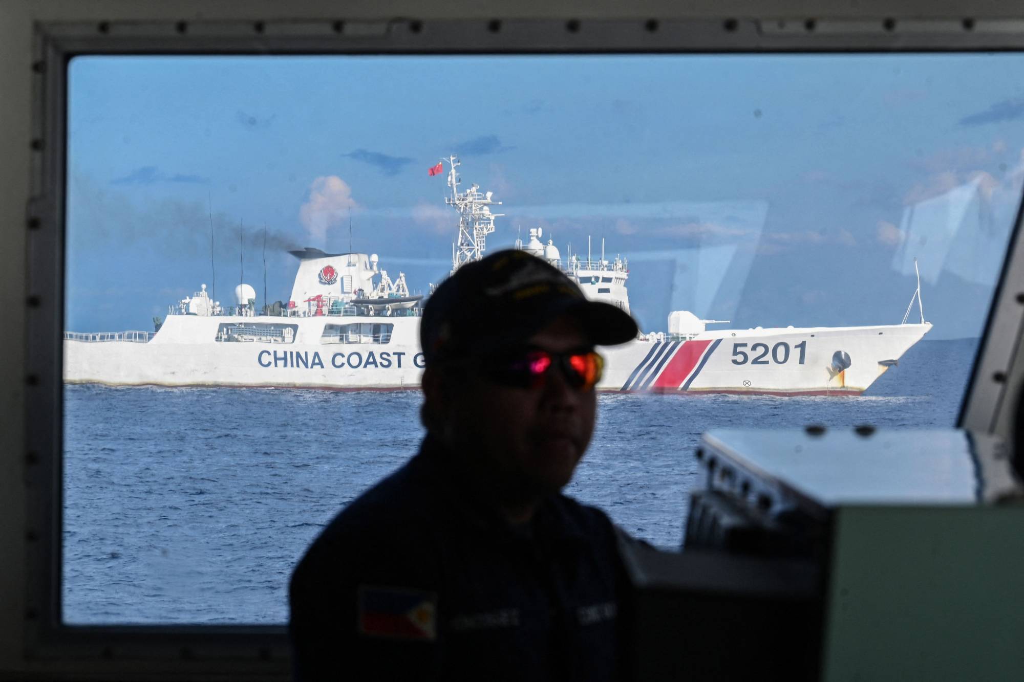 A member of the Philippine Coast Guard mans his post while his vessel is shadowed by a China Coast Guard ship at Second Thomas Shoal in the Spratly Islands of the disputed South China Sea on April 22.  | AFP-JIJI