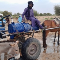 Mahamat Bechir Abdallah, a Sudanese refugee, fills a container as he sells water to the other refugees near the border between Sudan and Chad, in Koufroun, Chad, on Monday. | REUTERS
