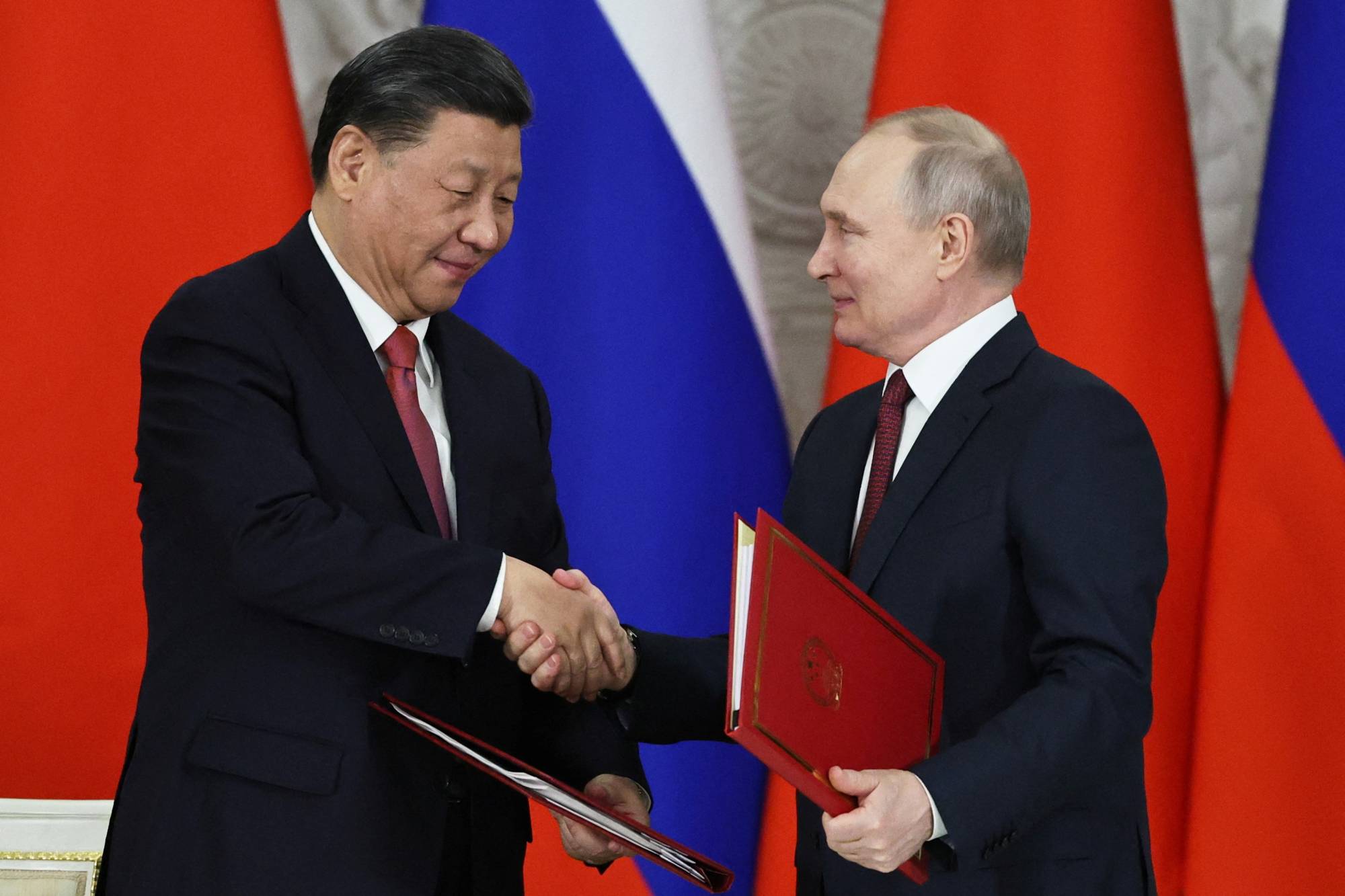 Chinese President Xi Jinping shakes hands with Russian President Vladimir Putin during a signing ceremony following talks at the Kremlin in Moscow on March 21. | POOL / SPUTNIK / VIA REUTERS