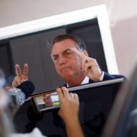 Former Brazilian President Jair Bolsonaro gestures to members of the media as he leaves his home following a search operation in Brasilia on Wednesday. | REUTERS
