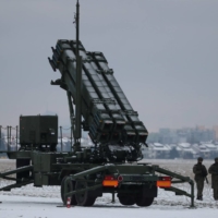Servicemen patrol in front of a Patriot air defense system during Polish military training at the airport in Warsaw on Feb. 7. The first of the systems to reach Ukraine arrived last month. | REUTERS