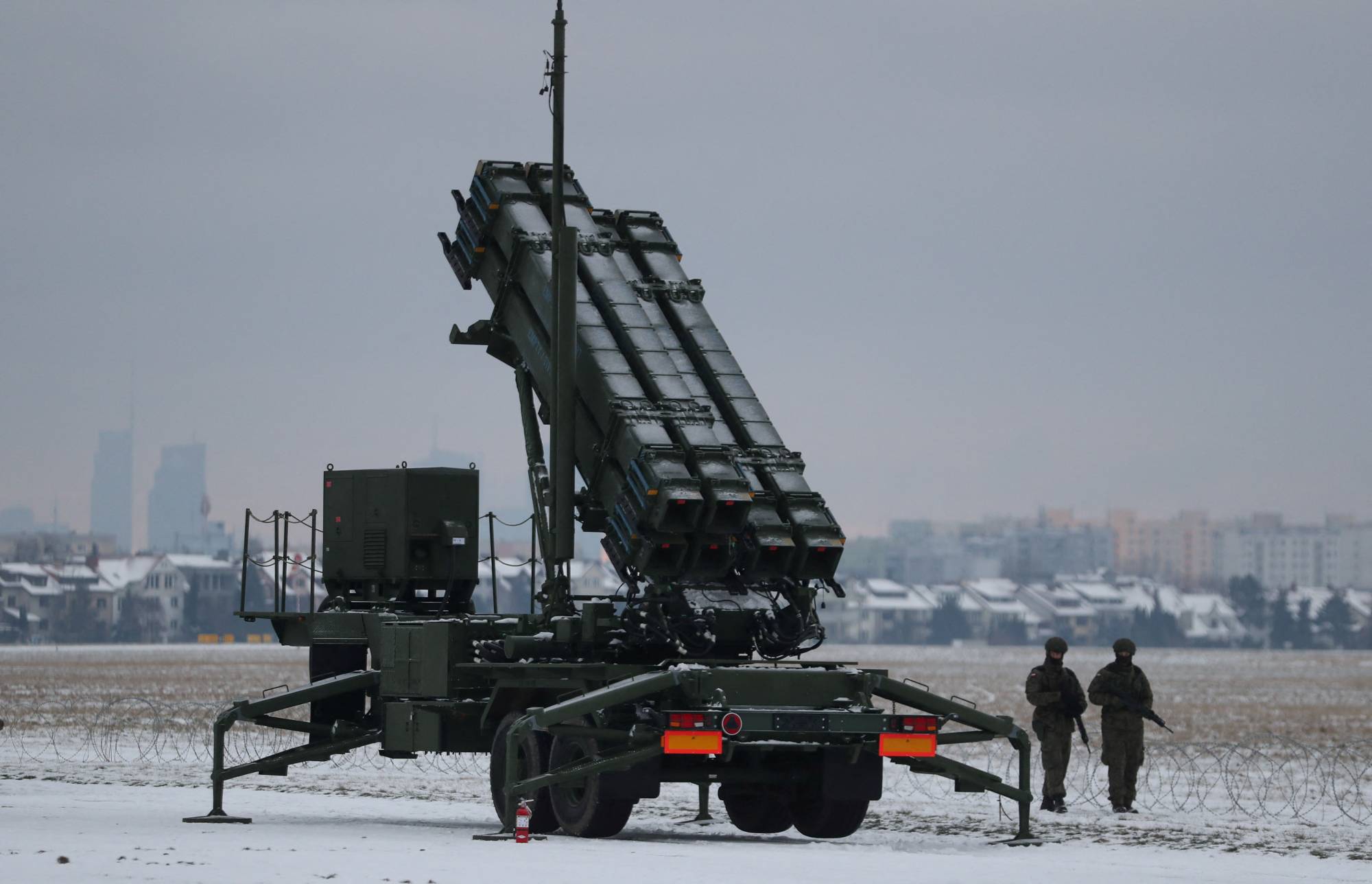 Servicemen patrol in front of a Patriot air defense system during Polish military training at the airport in Warsaw on Feb. 7. The first of the systems to reach Ukraine arrived last month. | Reuters