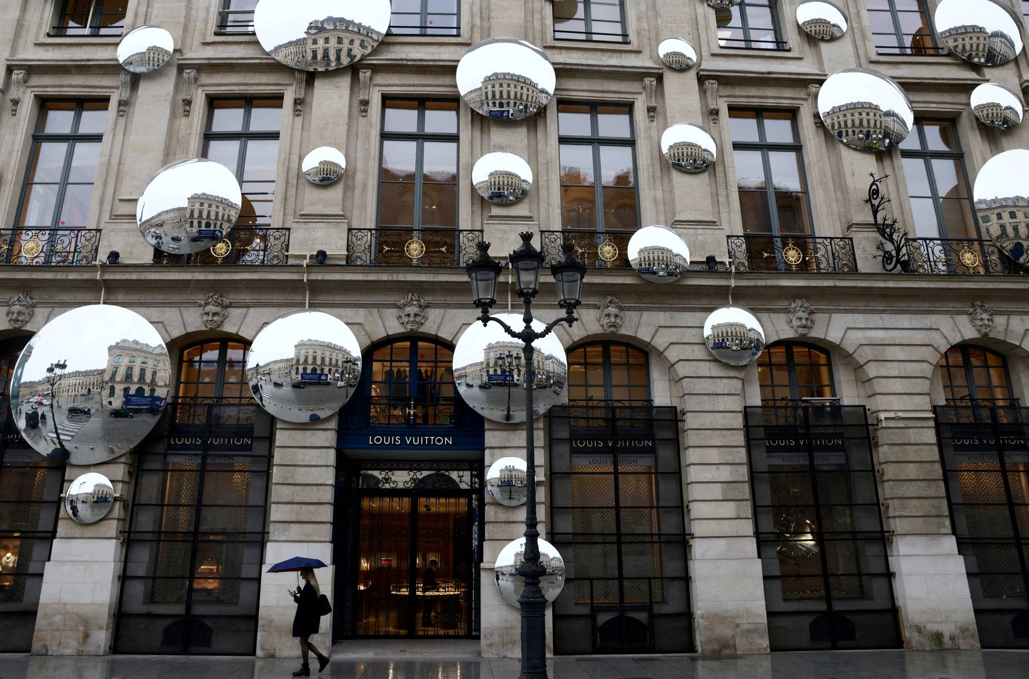 A pedestrian walks past the luxury retailer Louis Vuitton store at Place Vendome in Paris on March 22.  | REUTERS