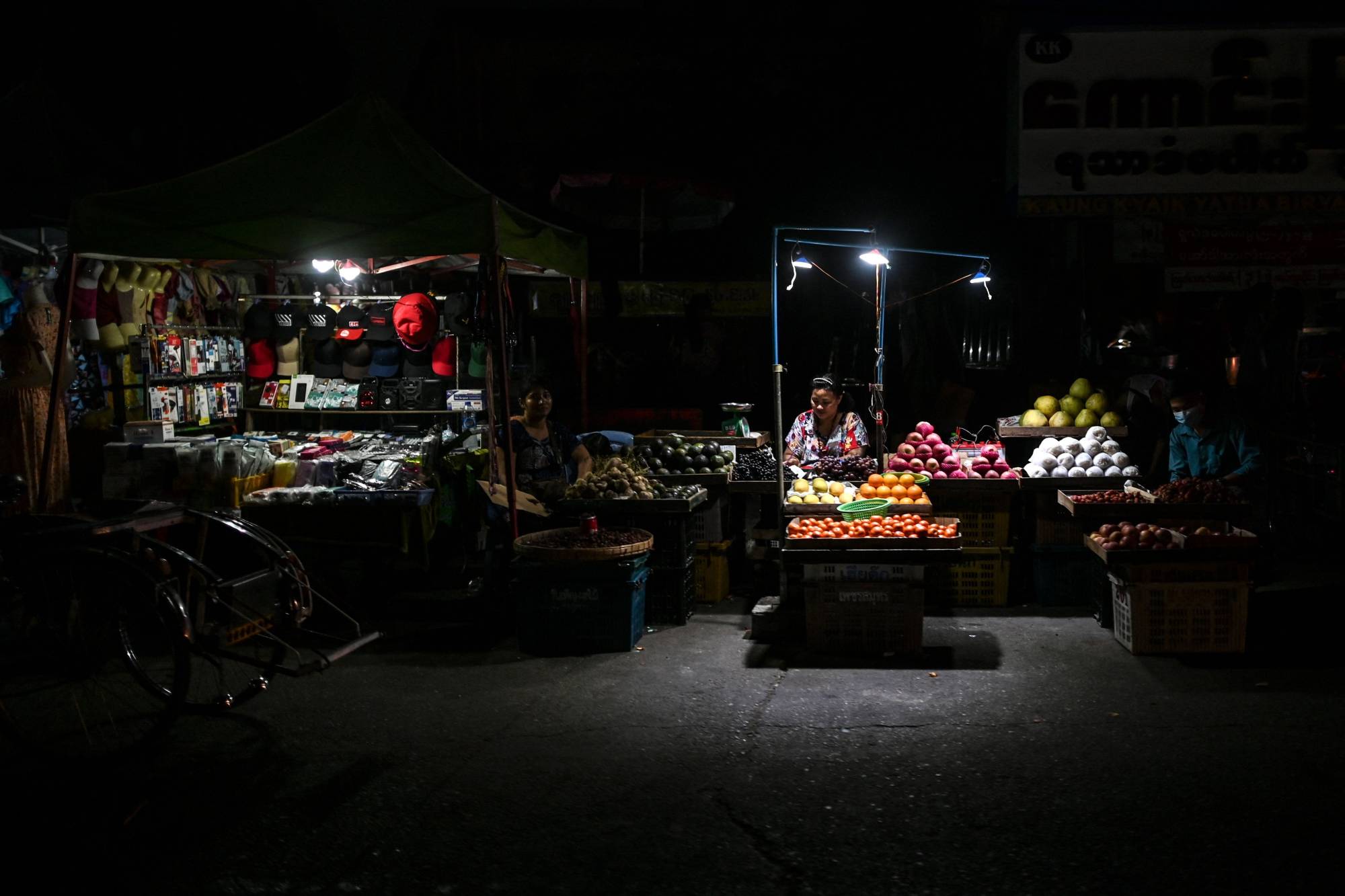 Street vendors wait for customers during a power outage in Yangon on March 3 | AFP-JIJI