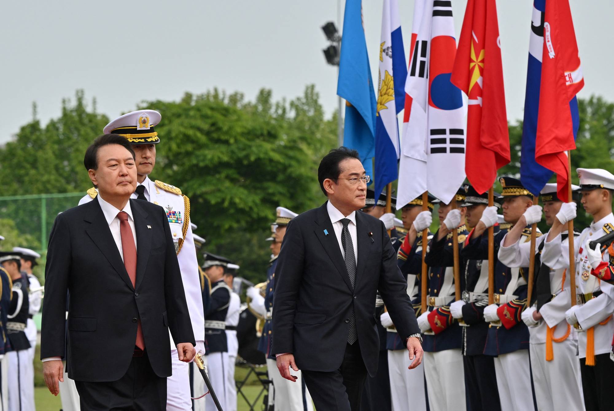 Prime Minister Fumio Kishida and South Korean President Yoon Suk-yeol attend a welcoming ceremony at the Presidential Office in Seoul before talks on Sunday. | POOL / VIA REUTERS