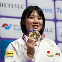 Saki Niizoe poses on the podium after winning gold at the World Judo Championships in Doha on Thursday. | AFP-JIJI