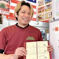 Kazuyoshi Igei displays some of the messages written by children and their supporters at Taco Spoon in Naha. | THE OKINAWA TIMES

