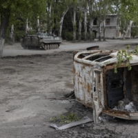 A Ukrainian BMP infantry fighting vehicle passes a destroyed car in Chasiv Yar, a small town west of Bakhmut, Ukraine, on Tuesday.  | TYLER HICKS / THE NEW YORK TIMES