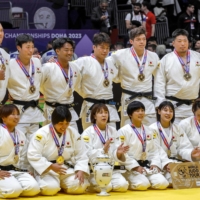 The Japanese team poses after winning gold in the mixed team competition during the judo world championships in Doha on Sunday. | AFP-JIJI