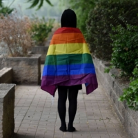 A gay student poses with a rainbow flag in Beijing. Last summer, two students at a prestigious Chinese university were issued warnings for distributing LGBTQ rainbow flags on campus. | AFP-JIJI