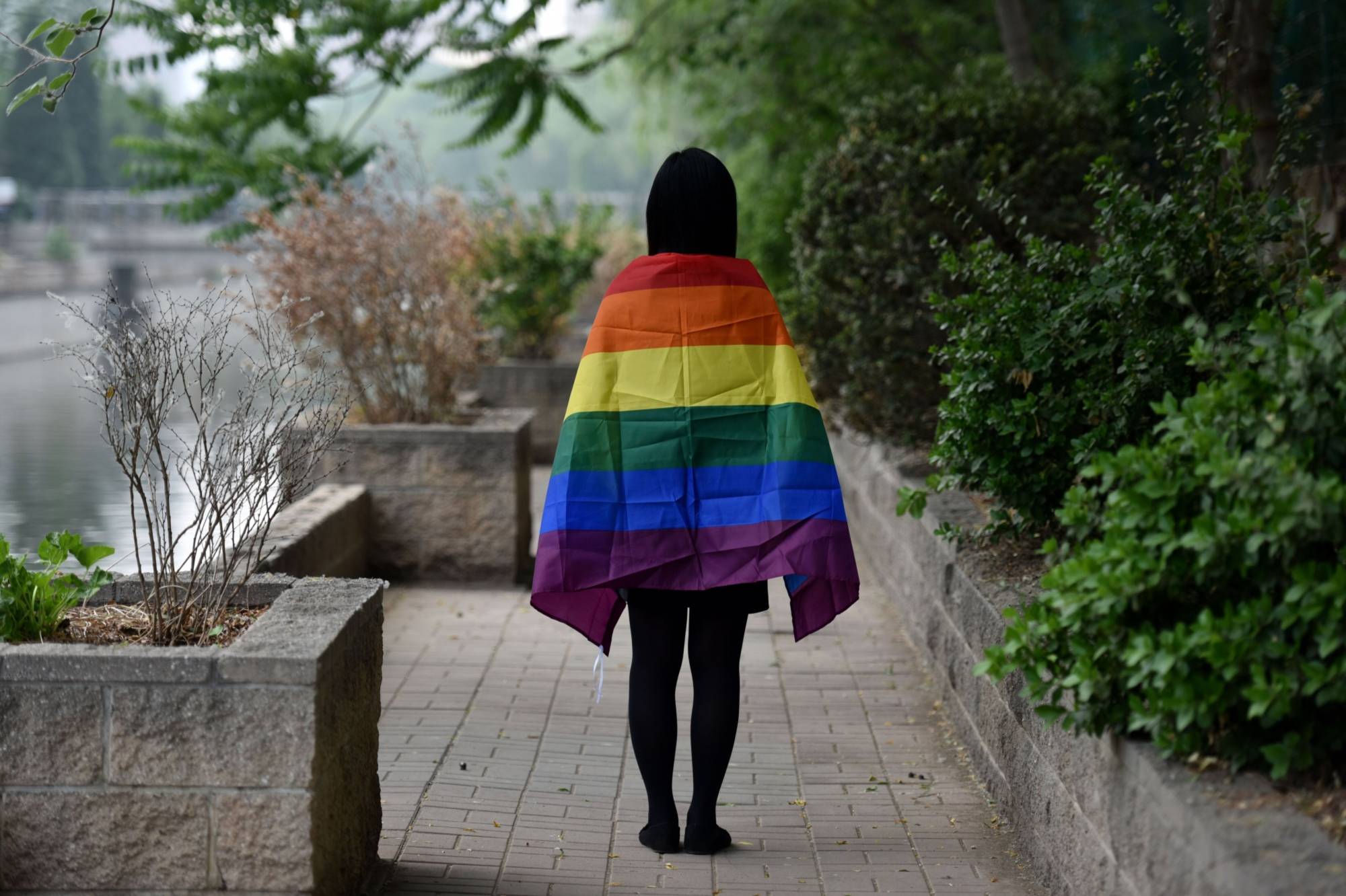 A gay student poses with a rainbow flag in Beijing. Last summer, two students at a prestigious Chinese university were issued warnings for distributing LGBTQ rainbow flags on campus. | AFP-JIJI