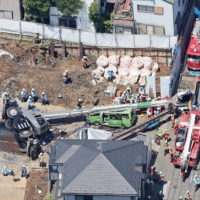 Cars are crushed by a toppled mobile crane at a construction site in Tokyo\'s Shinagawa Ward on Tuesday. | KYODO