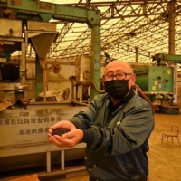 Tomoyuki Nagata holds pellets made from compost at a processing facility in Koshi, Kumamoto Prefecture. | NISHINIPPON SHIMBUN