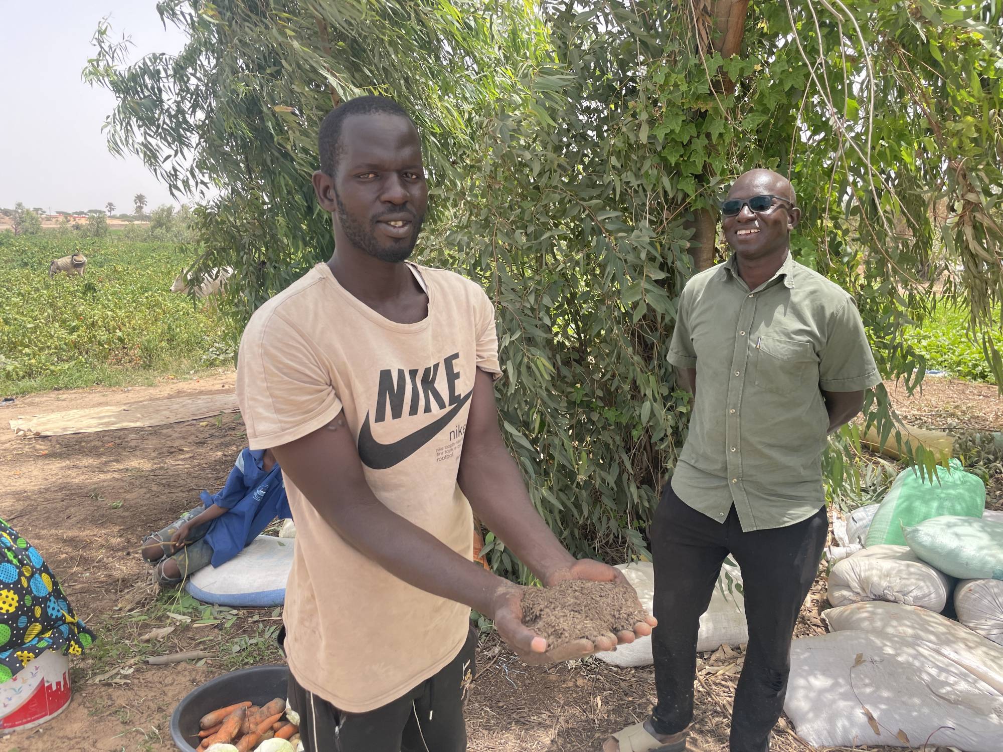 Vegetable grower Fallou Faye (left) holds a bokashi mixture in Mboro, Senegal, on March 25. | JACK THOMPSON