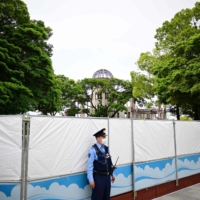 A police officer stands guard in front of a closed entrance of Peace Memorial Park in Hiroshima on Thursday.  | AFP-JIJI