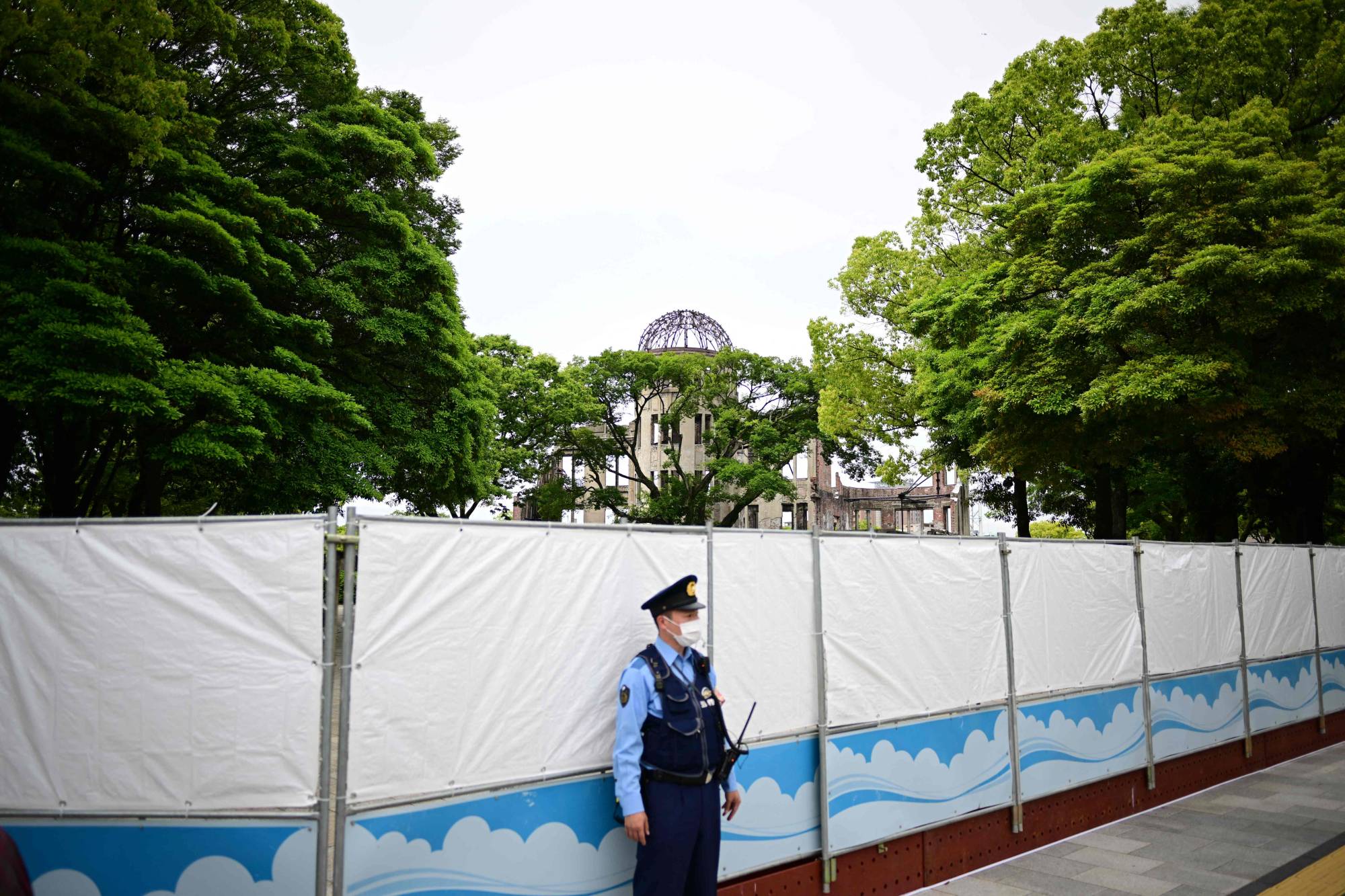 A police officer stands guard in front of a closed entrance of Peace Memorial Park in Hiroshima on Thursday. | AFP-JIJI