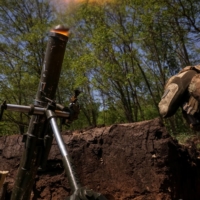A Ukrainian service member from a 28th separate mechanized brigade fires a mortar at his position at a front line near the city of Bakhmut in the Donetsk region, Ukraine, on Thursday. | REUTERS