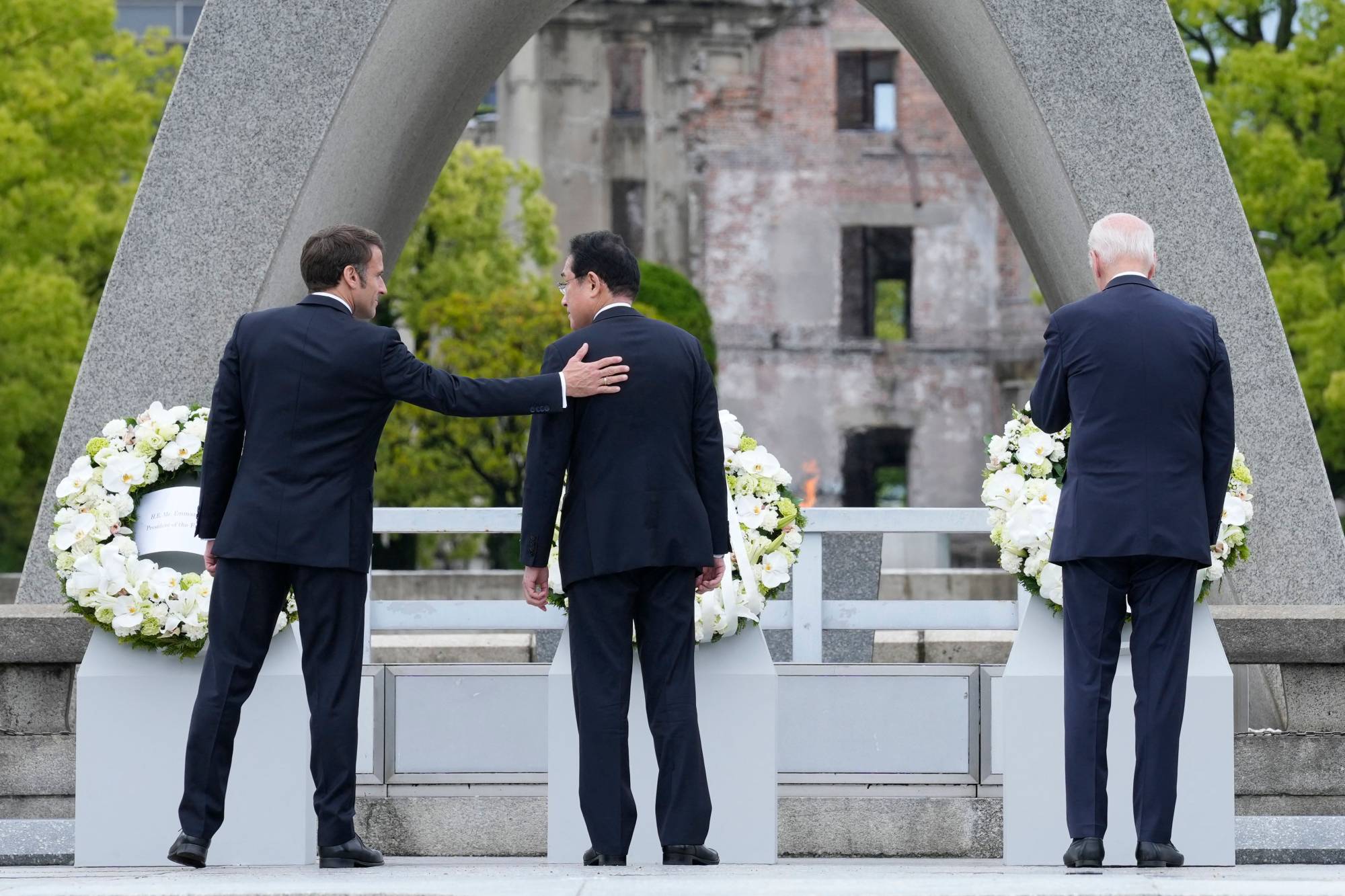 French President Emmanuel Macron, Prime Minister Fumio Kishida and U.S. President Joe Biden lay flower wreaths at the cenotaph for Atomic Bomb Victims in the Peace Memorial Park in Hiroshima on Friday. | POOL / VIA AFP-JIJI