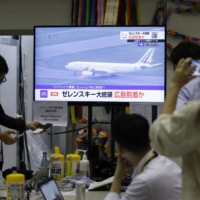 A live broadcast shows an airplane carrying Ukrainian President Volodymyr Zelenskyy arriving at Hiroshima Airport, on a monitor at the Group of Seven media center in Hiroshima on Saturday. | BLOOMBERG