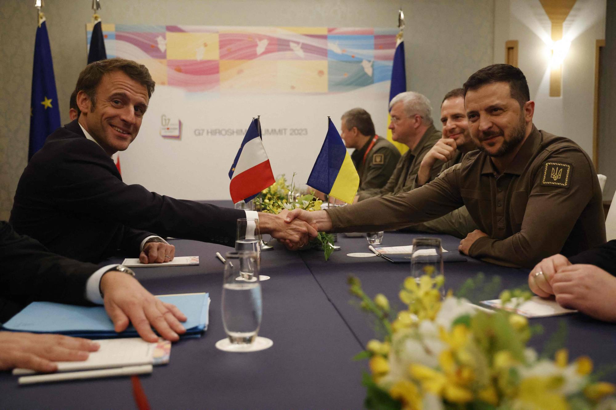 Ukrainian President Volodymyr Zelenskyy shakes hands with French President Emmanuel Macron during their bilateral meeting on the sidelines of the Group of Seven leaders' summit in Hiroshima on Saturday. | AFP-JIJI