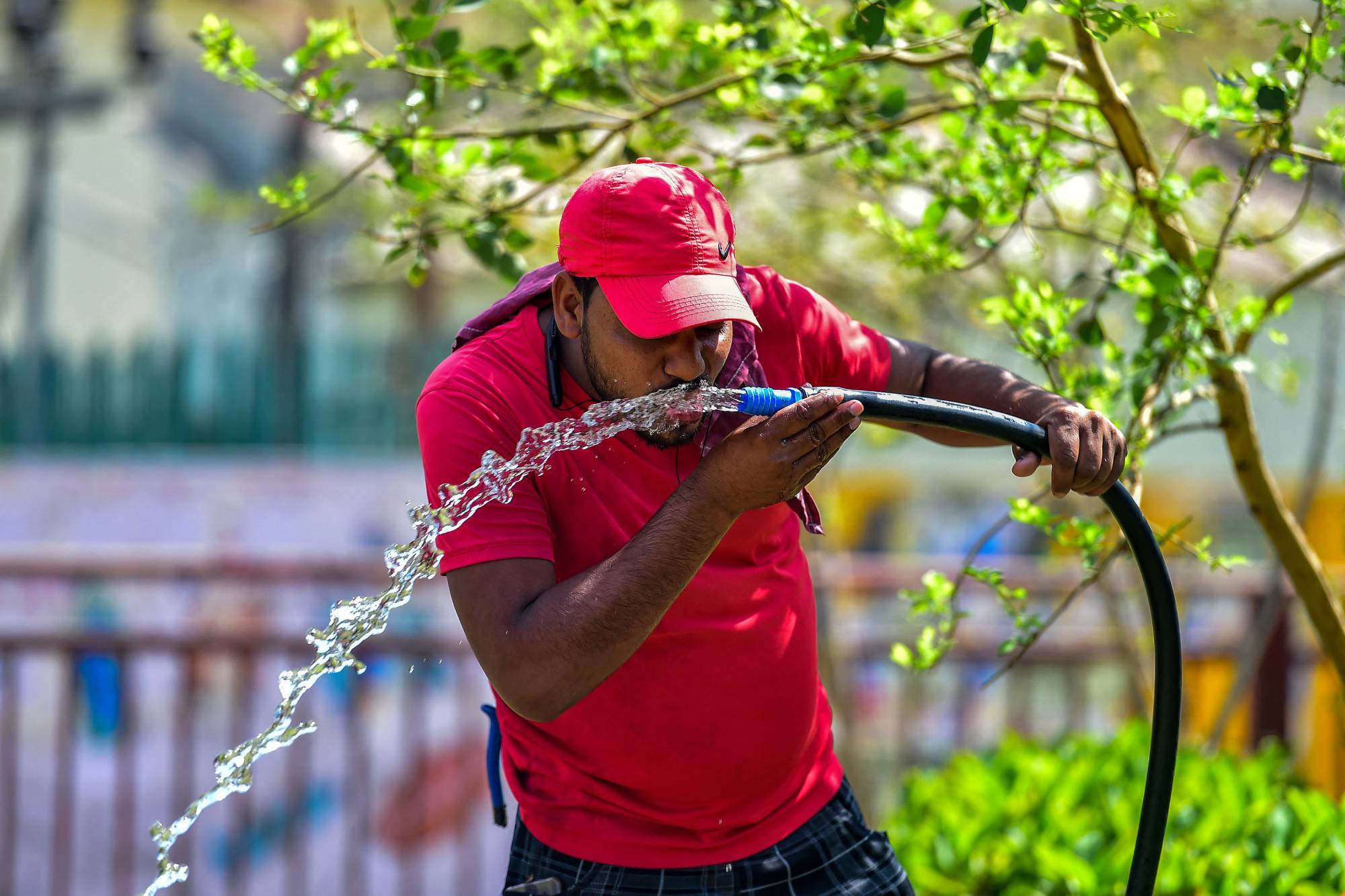 A man drinks from a hose on a hot summer afternoon in Prayagraj, India, earlier this month.  | AFP-JIJI