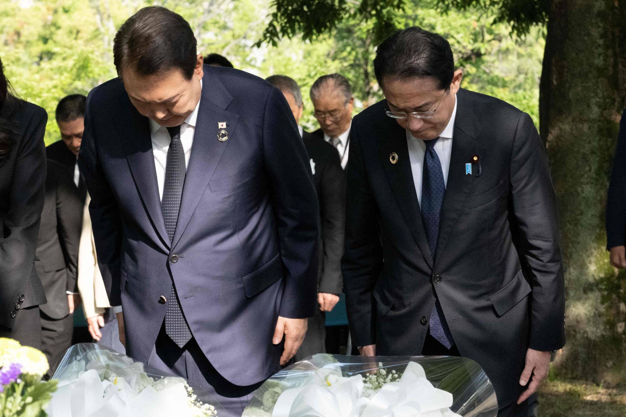 South Korean President Yoon Suk-yeol and Prime Minister Fumio Kishida bow as they lay flowers at the cenotaph dedicated to Korean victims of the 1945 atomic bombing of Hiroshima on Sunday. | POOL / VIA AFP-JIJI