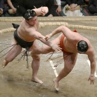 Wakamotoharu (left) wins his bout against Hoshoryu on Day 9 of the Summer Grand Sumo Tournament. | KYODO