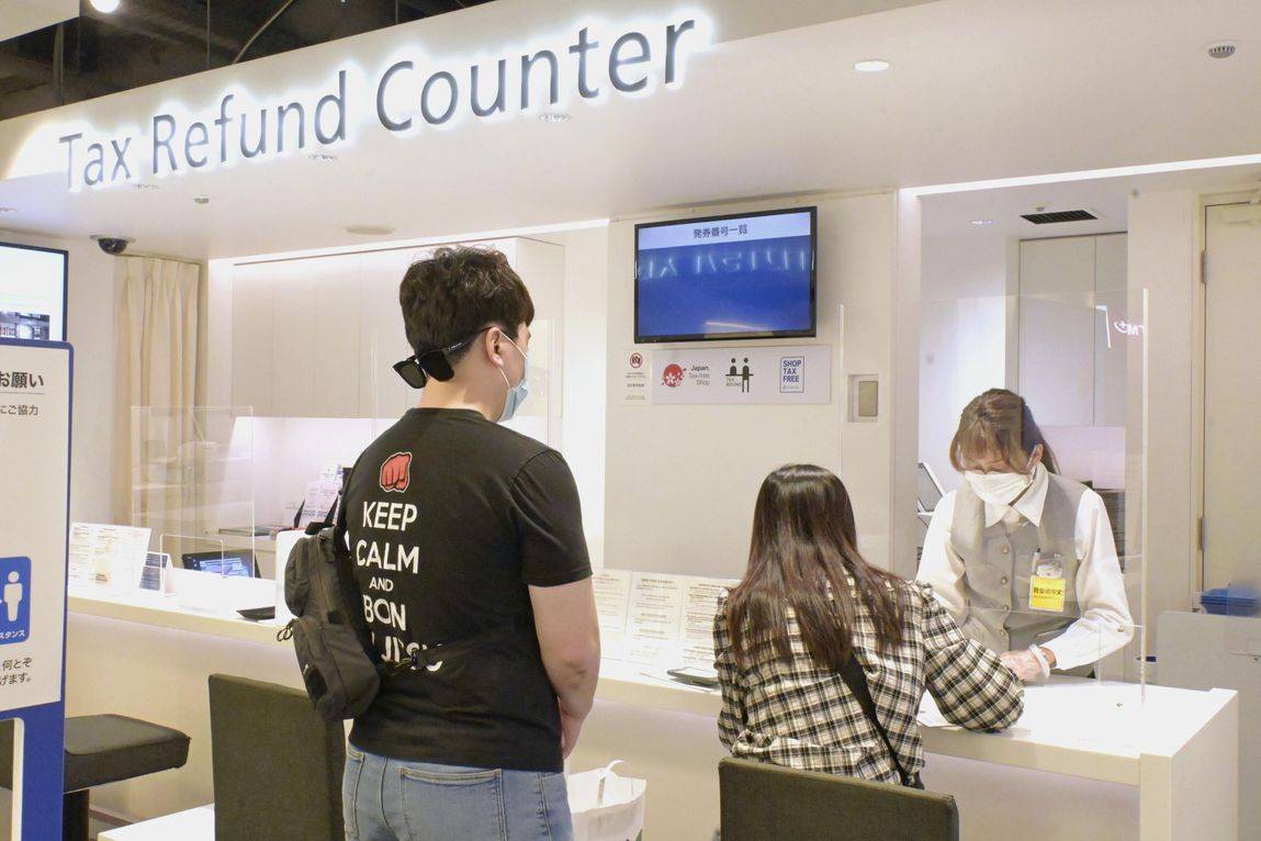 A traveler from overseas fills in a form for a tax-free purchase at a department store in Tokyo in October. | KYODO