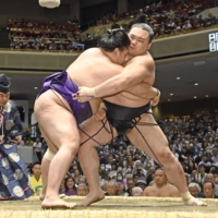 Asanoyama (right) grapples with Meisei during Day 11 of the Summer Grand Sumo Tournament at Ryogoku Kokugikan on Wednesday. | KYODO
