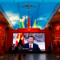 Visitors stand in front of a giant screen displaying Chinese leader Xi Jinping next to a flag of the Communist Party of China, at the Military Museum of the Chinese People\'s Revolution in Beijing last October. | REUTERS