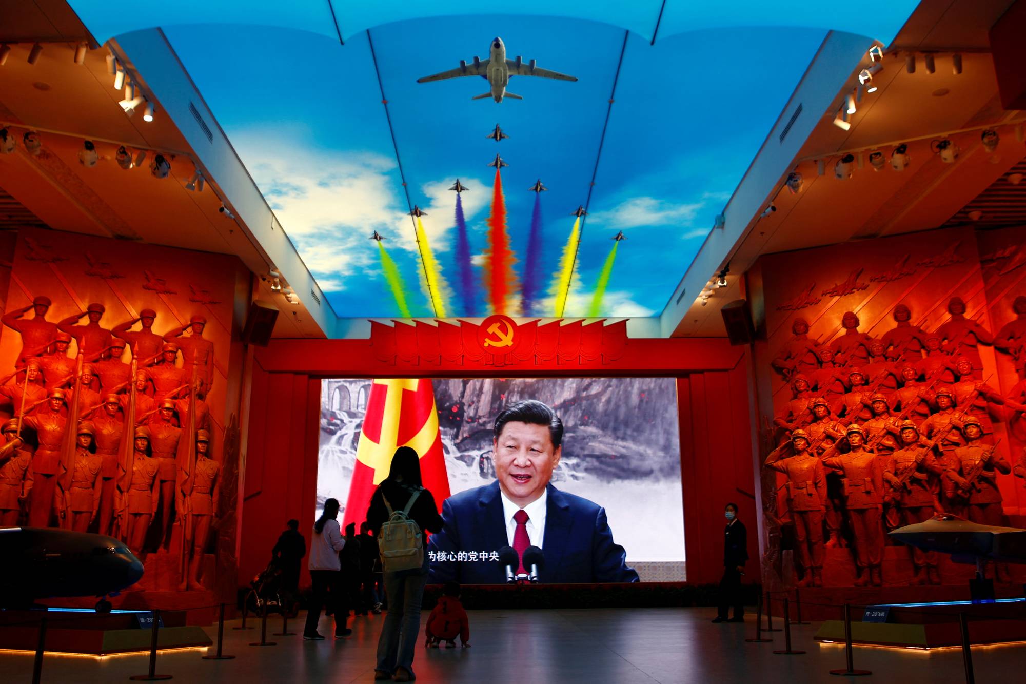 Visitors stand in front of a giant screen displaying Chinese leader Xi Jinping next to a flag of the Communist Party of China, at the Military Museum of the Chinese People's Revolution in Beijing last October. | REUTERS