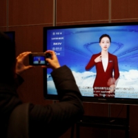 A journalist documents a screen displaying a digital sign-language system run by an artificial intelligence system, during a media tour to the Beijing Academy of Artificial Intelligence in Beijing in February last year. | REUTERS