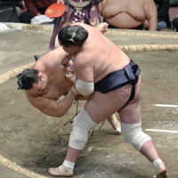 Yokozuna Terunofuji throws down Asanoyama to win their bout during the Summer Grand Sumo Tournament at Ryogoku Kokugikan on Friday. | KYODO