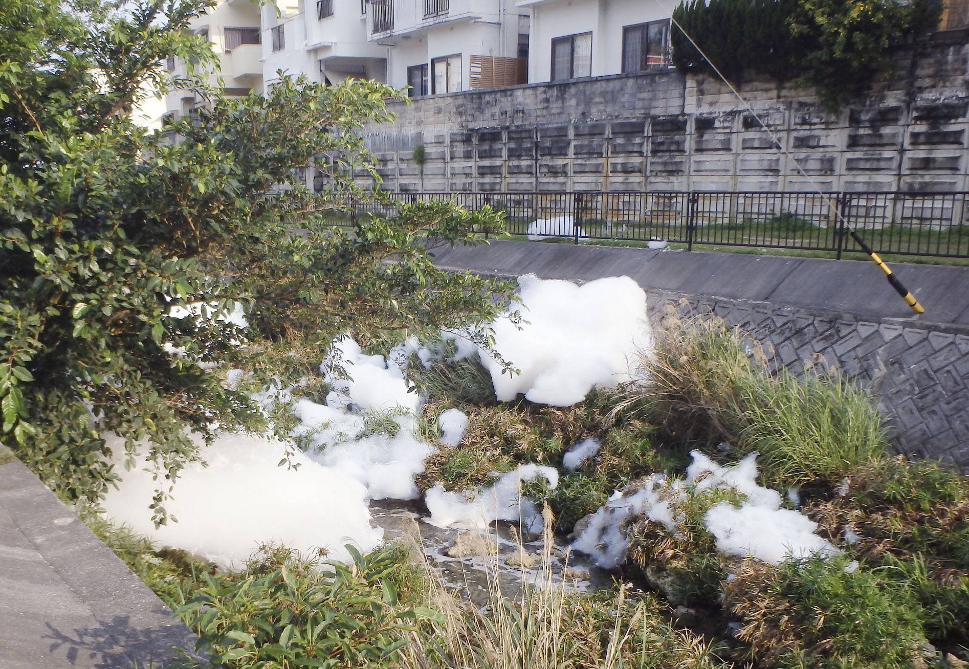 Firefighting foam containing the potentially hazardous chemical PFOS are seen on April 11, 2020, after spilling out from U.S. Marine Corps Air Station Futenma into a residential area in the city of Ginowan, Okinawa Prefecture. | THE CITY OF GINOWAN / VIA KYODO