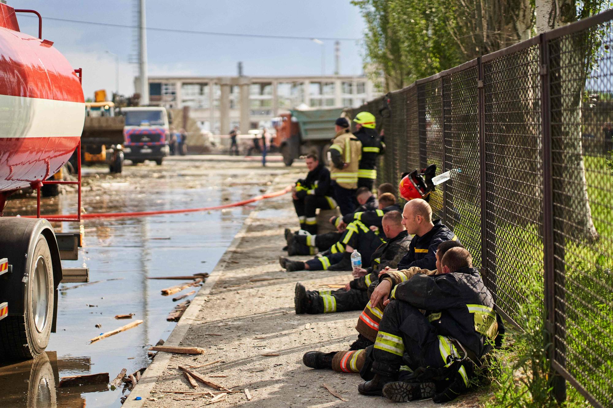 Firefighters rest after a medical facility was hit by a missile, in the city of Dnipro, Ukraine, on Friday. | AFP-JIJI