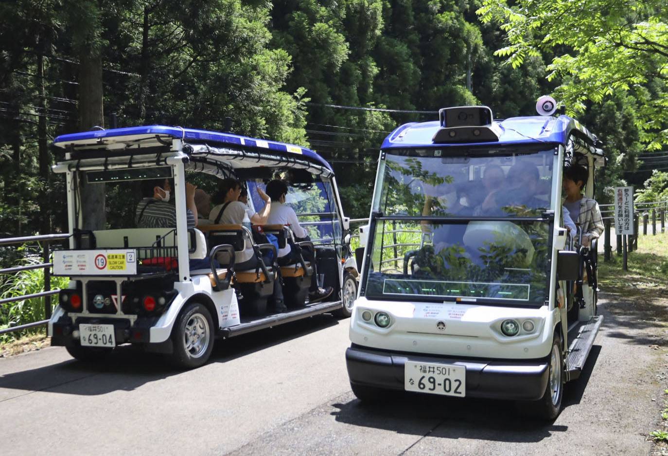 Self-driving vehicles carrying passengers run on a walking trail in Eiheiji, Fukui Prefecture, on Sunday as part of Japan's first transportation service based on so-called level 4 autonomous driving. | KYODO