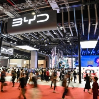 People walk past the BYD stand at the 20th Shanghai International Automobile Industry Exhibition on April 18. | AFP-JIJI