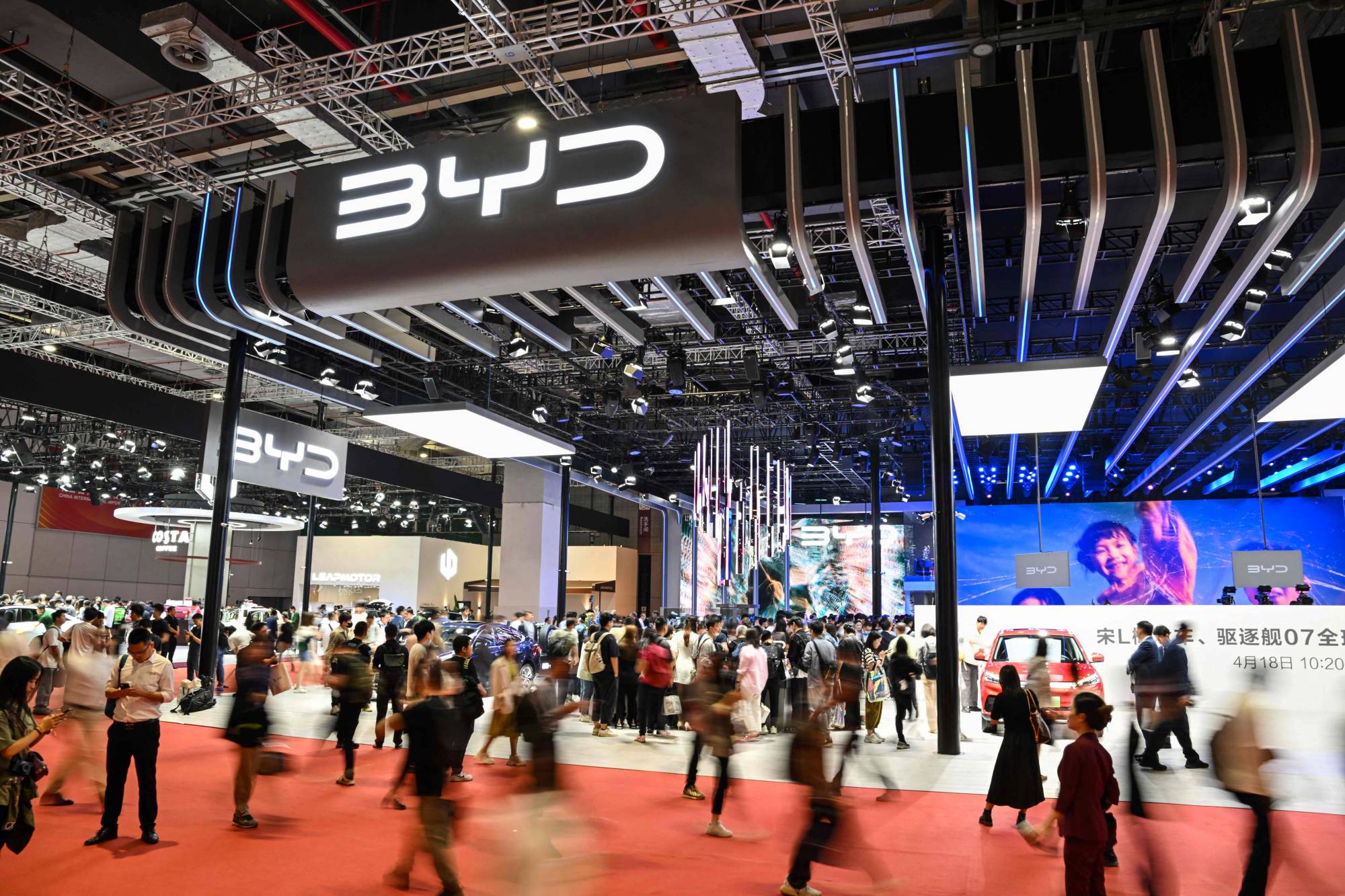 People walk past the BYD stand at the 20th Shanghai International Automobile Industry Exhibition on April 18. | AFP-JIJI
