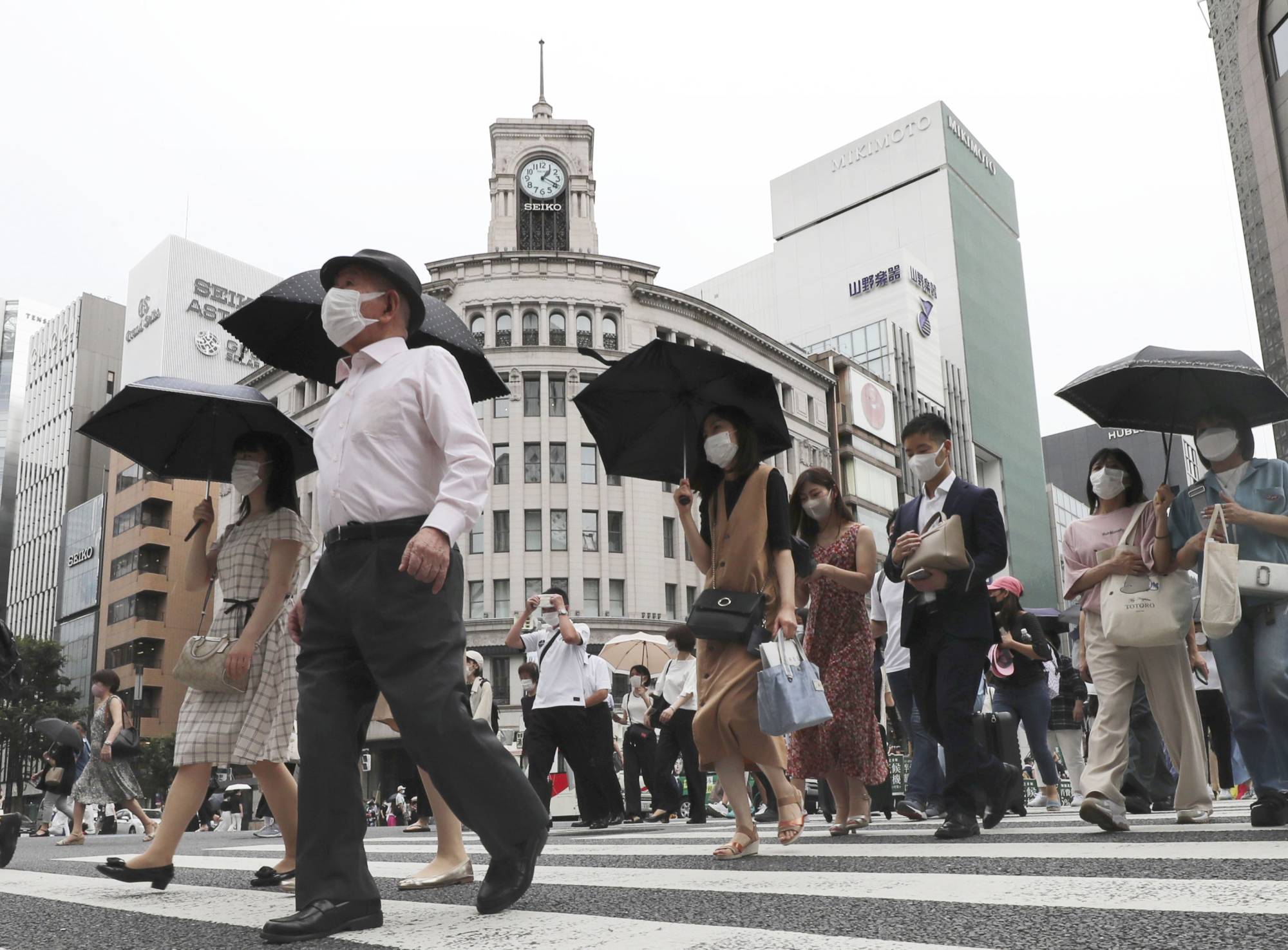 People walk in extreme heat in Tokyo as the city marks a record ninth straight day of temperatures above 35 degrees Celsius on July 3, 2022. | KYODO