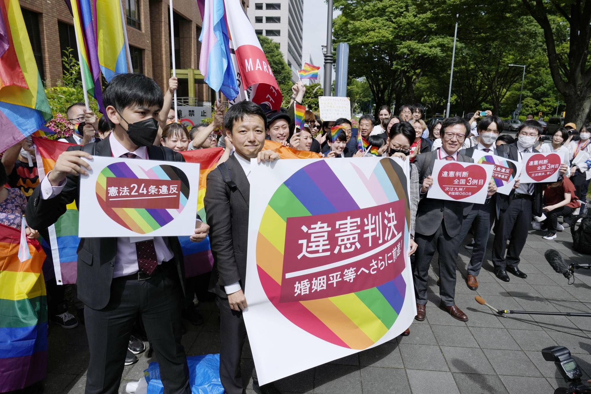 Lawyers for the plaintiffs hold signs Tuesday outside the Nagoya District Court after its ruling that not allowing same-sex marriage is unconstitutional. | KYODO